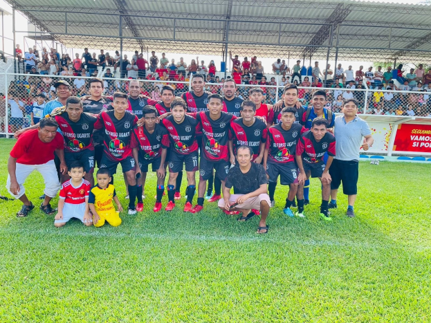 Gruppe von Männern feiert auf einem Fußballfeld mit einem "Fotos Ugarte U-17 vs U-18"-Schild nach einem Match-Sieg.