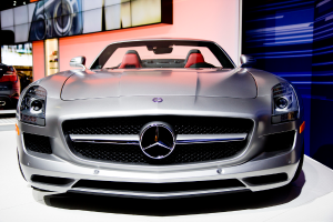 Mehrere Autos sind im Vordergrund geparkt, im Hintergrund ist ein digitaler Bildschirm an der Wand montiert.