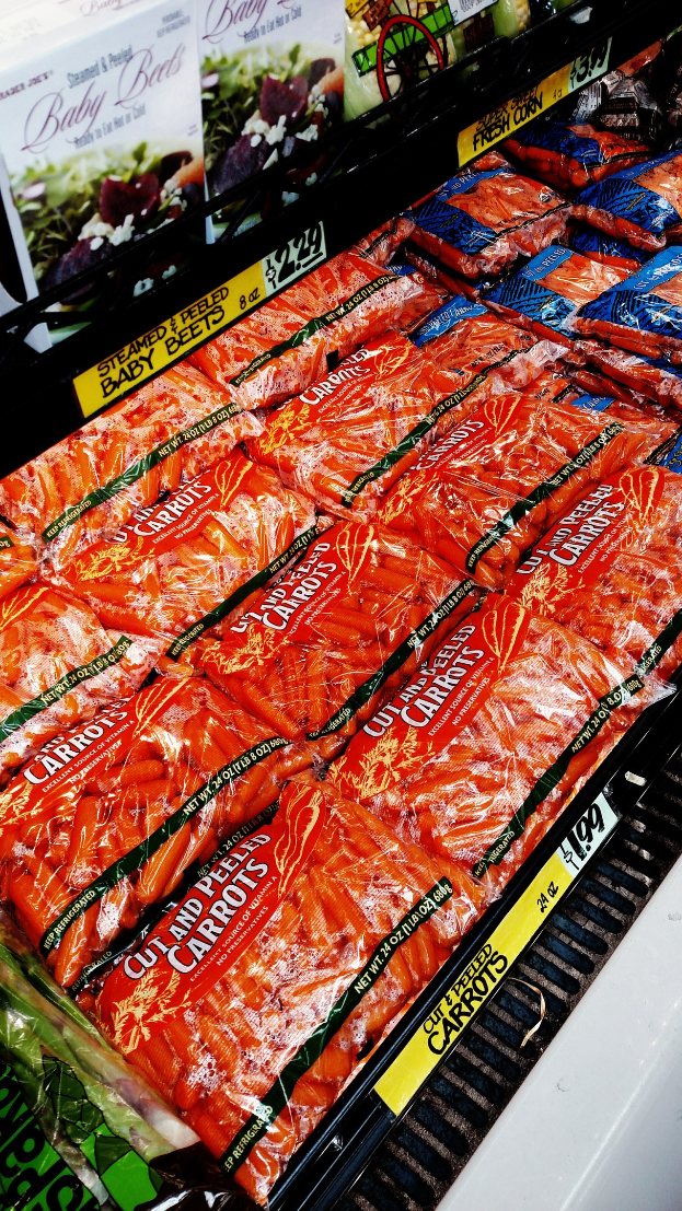 Geschäftsregal mit verschiedenen verpackten Lebensmitteln, darunter Gemüsepackungen, jeweils mit angebrachten Preisschildern.