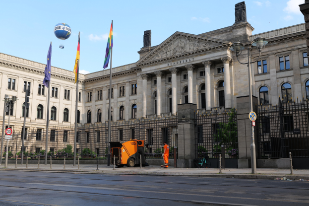Großer moderner Bau mit vielen Fenstern, als Bundestag in Berlin, Deutschland identifiziert, umgeben von Straßeninfrastruktur und Passanten unter einem bewölktem Himmel.