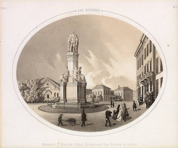 Schwarze und weiße Zeichnung der Statue des Heiligen Majestät König Maximilian I. von Bayern in einem Stadtplatz, umgeben von Gebäuden, Bäumen und Menschen, mit Text unten und Himmel im Hintergrund.