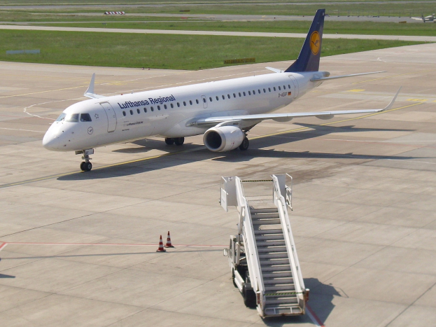 Lufthansa Regional Airbus A320-200 auf dem Frankfurter Flughafen-Rollfeld mit Verkehrskegeln, einem mobilen Treppenfahrzeug, grünem Gras, Bäumen und einem klaren blauen Himmel.