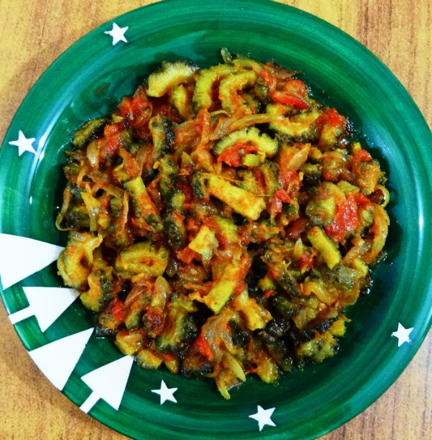 Ein grünes Teller auf einem hölzernen Tisch hält eine Schüssel Zucchini-Fettuccine Alfredo mit leuchtenden Gemüsen einschließlich Zucchinis, Paprika, Zwiebeln und Pilzen in einer würzigen Sauce.