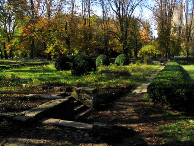 Ein Park mit einer gewundenen Steintreppe, grünem Gras, Pflanzen, Bäumen, Stufen, die nach oben führen, und einem sichtbaren Himmel im Hintergrund.