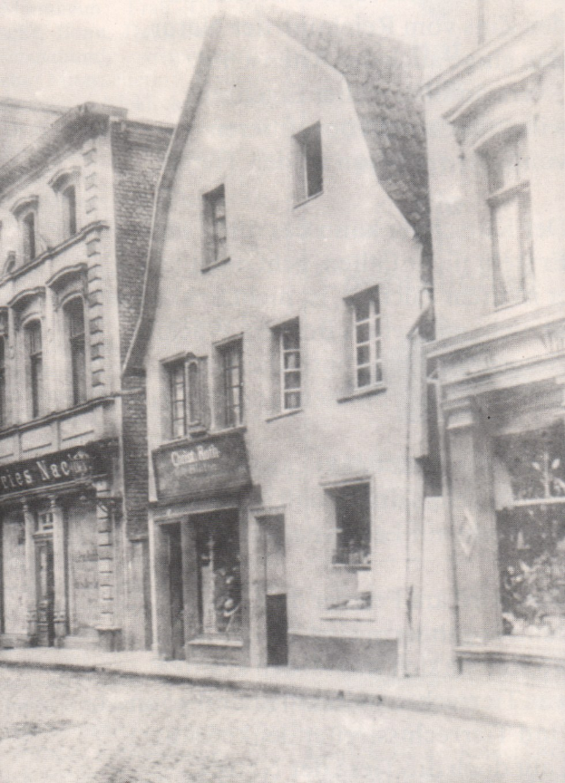 Schwarz-weiß-Bild einer Straße mit Häusern, die Fenster und Schilder zeigen, und einer Straße unten.