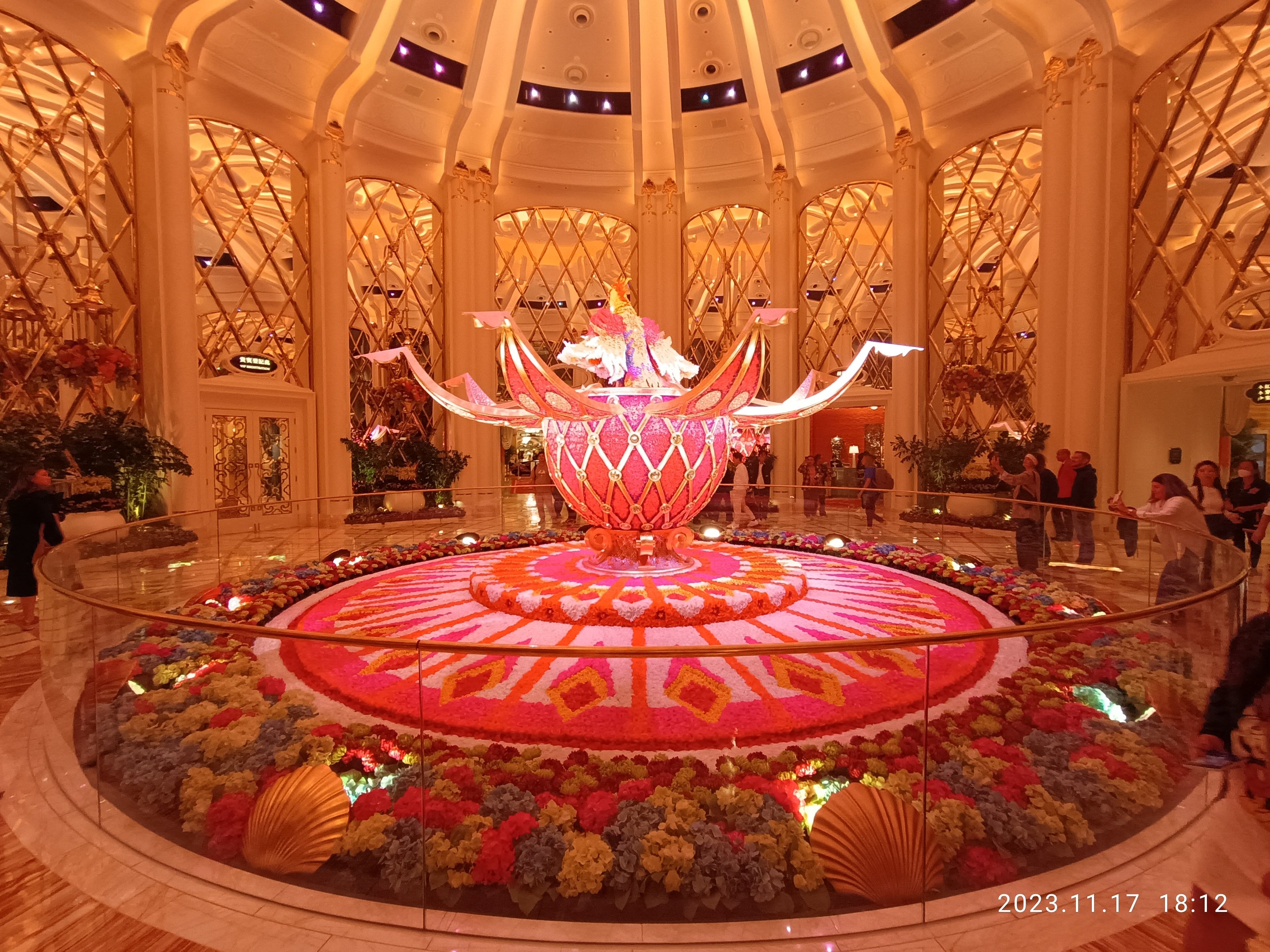 Außenansicht des Bellagio Hotels und Casinos in Las Vegas, Nevada, mit Menschen, dekorativen Blumenarrangements, Säulen und Lichtern, einschließlich eines Wasserzeichens unten.