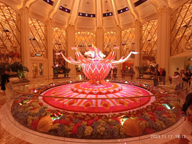 Außenansicht des Bellagio Hotels und Casinos in Las Vegas, Nevada, mit Menschen, dekorativen Blumenarrangements, Säulen und Lichtern, einschließlich eines Wasserzeichens unten.