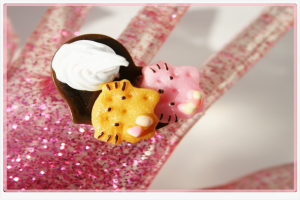 Eine künstliche Glitzerhand, die eine Tasse Kuchen und Gelees hält.