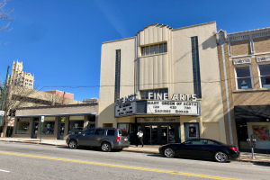 Außenansicht des Feinschmecker-Theaters in St. Louis, Missouri, mit Fahrzeugen auf der Straße, einem Fußgänger auf dem Gehweg, einer Wegweiser, Bäumen, Gebäuden und Himmel.