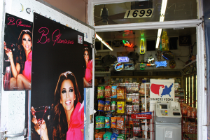 Eine Innenaufnahme mit einer Tür, die Plakate einer Frau auf der linken Seite, verschiedenen Ladeneinrichtungsgegenständen in der Mitte, einem Geldautomaten und einer Texttafel auf der rechten Seite sowie einer Nummernleiste oben zeigt.