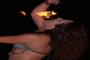 Eine Frau steht über einem Ort und versucht, ein brennendes Objekt in ihrer Hand zu essen.