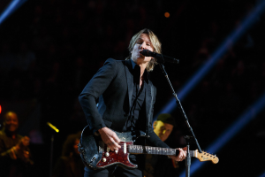 Keith Urban performs auf der Bühne im Joint im Hard Rock Hotel & Casino in Las Vegas, spielt Gitarre mit einem Mikrofon vor sich und Bandmitgliedern im Hintergrund bei gedämpftem Licht.
