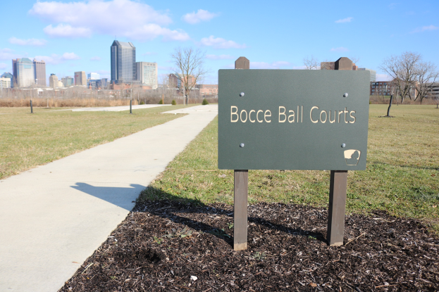 Ein Schild am Boden neben einem Weg und Bäumen weist auf Boule-Plätze in Indianapolis, Indiana, hin.