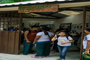 Ein Geschäft mit einer Eisenblechfassade und einem Schild mit Text oben, mit Menschen drinnen.