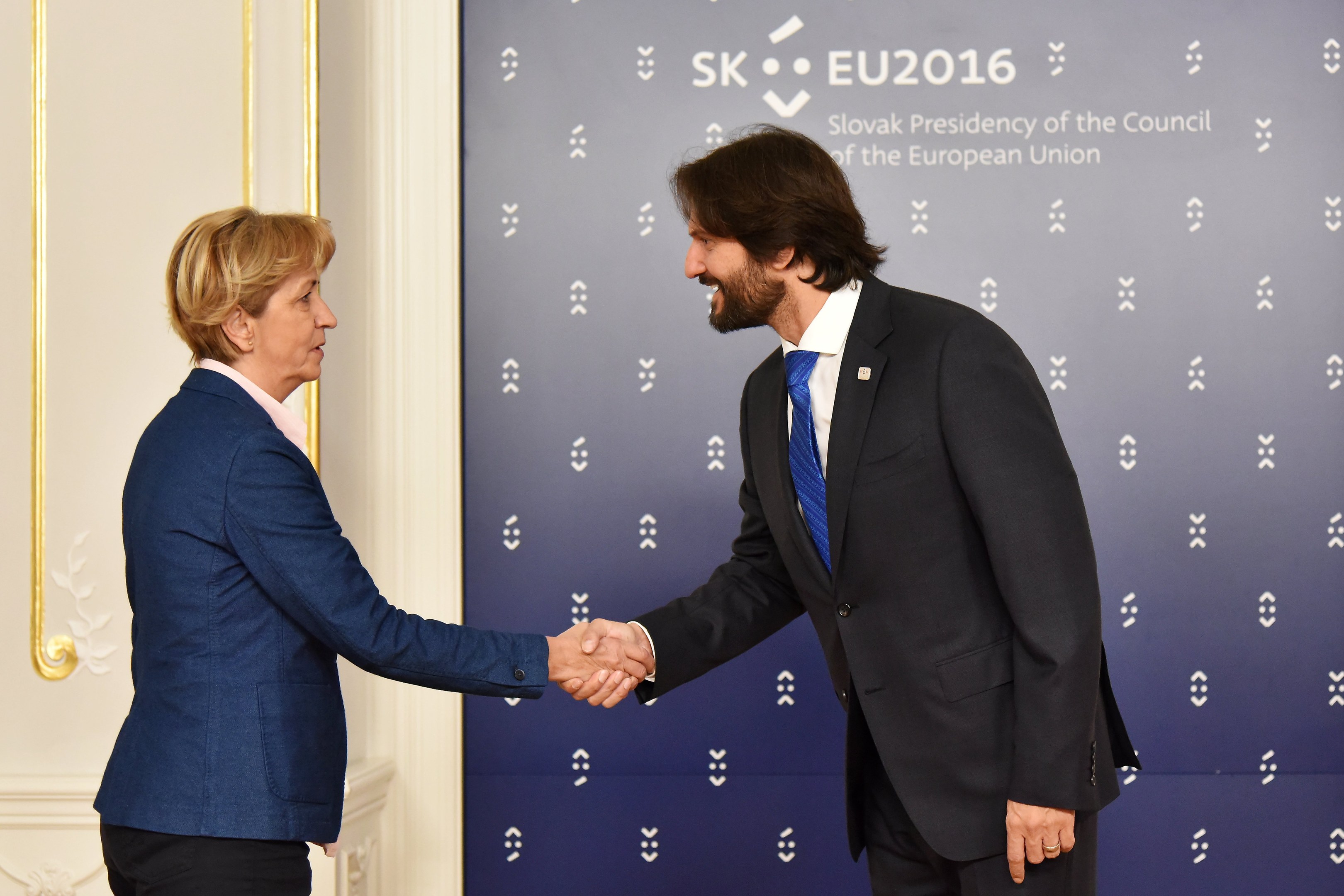 Bundeskanzlerin Angela Merkel und Joachim Gauck geben sich die Hand bei einem EU-Gipfeltreffen und l├Ącheln