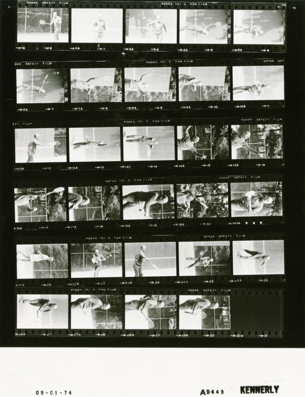 Schwarzes und weißes Foto eines Mannes in einem weißen Hemd und Shorts, der konzentriert Tennis spielt und einen Schläger in der rechten Hand hält, vor einem Filmstreifen-Hintergrund.