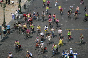 Menschen, die Fahrräder auf einem Weg mit Pfosten und einem Gehweg auf der linken Seite fahren.