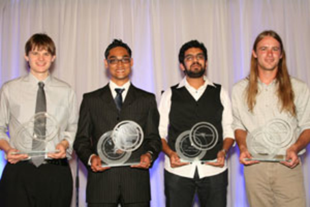 Vier Personen mit strahlenden Gesichtern, jede hält einen Pokal, mit einem Vorhang im Hintergrund.