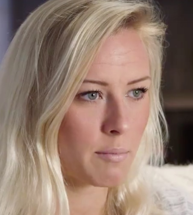 Blonde Frau mit blauen Augen in Not, Hintergrund unscharf, was darauf hindeutet, dass sie gezwungen wurde, die Show zu verlassen.