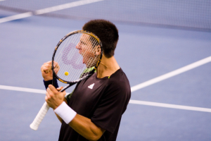 Eine Person hält einen Schläger und ein Netz im Hintergrund.