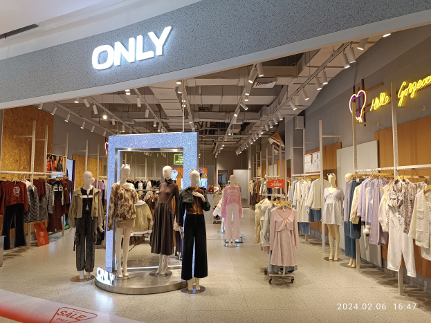 Der Innenraum eines Bekleidungsgesch├Ąfts mit Schaufensterpuppen in Kleidern, Kleiderb├╝geln, Texttafeln, Deckenleuchten und einem Wasserzeichen, das darauf hinweist, dass es das einzige Gesch├Ąft in Singapur ist.